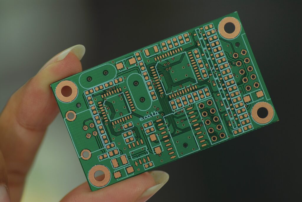 Płytka PCB trzymana w palcach.