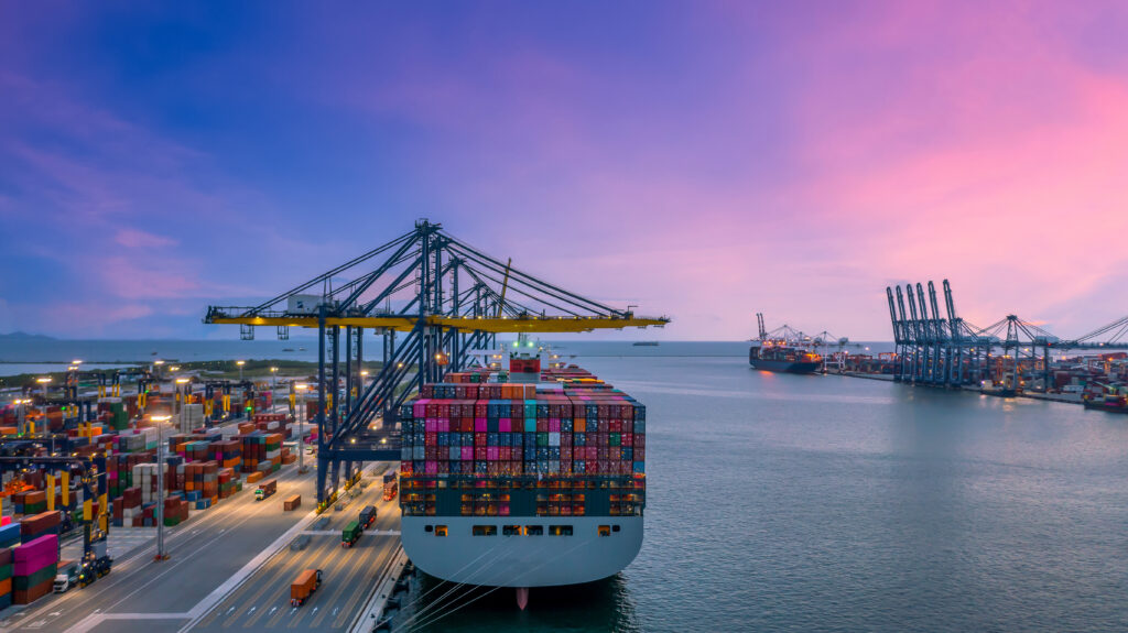Widok na port z przycumowanym statkiem transportowym załadowanym kontenerami.