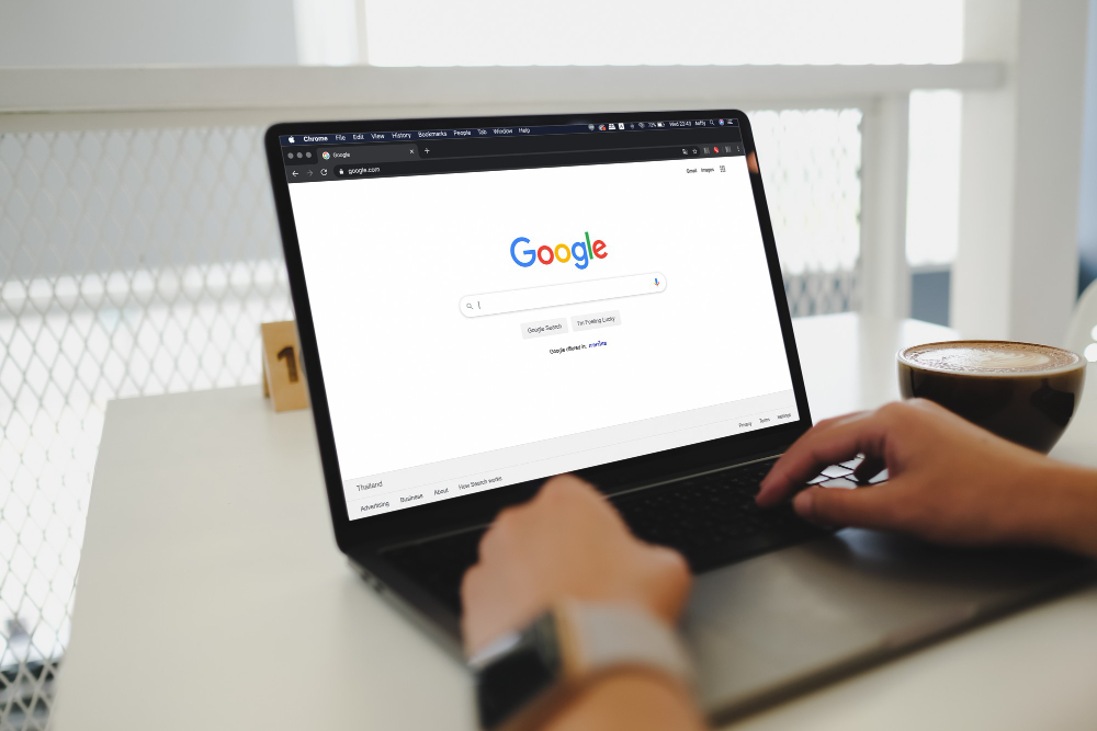 Osoba wyszukuje informacji w Google na laptopie w kawiarni.